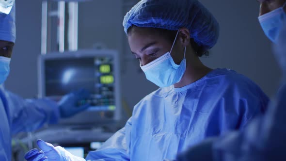 Mixed race surgeons wearing protective clothing performing surgery in operating theatre