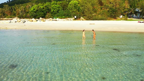 Beautiful ladies tanning on idyllic seashore beach adventure by blue green water and bright sand bac