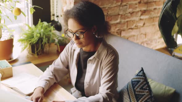 Afro-American Business Lady Working on Laptop at Cafe Table