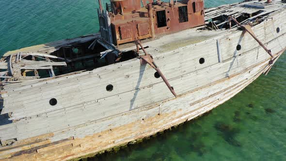 A Wrecked Wooden Ship Lies on the Seashore Covered with Rust