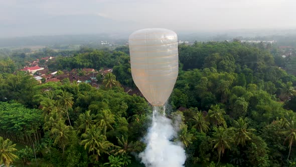 Hot air balloon with fire crackers rise over tropical landscape of Java Indonesia