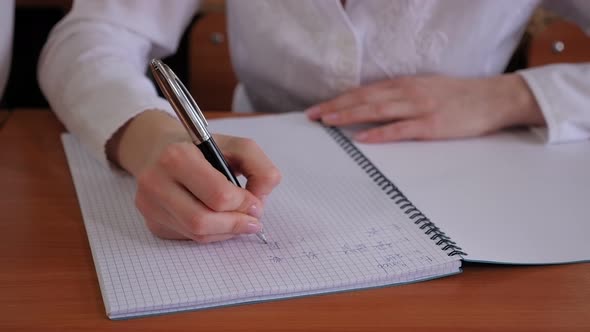 A Student Writing in a Math Notebook While Sitting at a Desk at the University