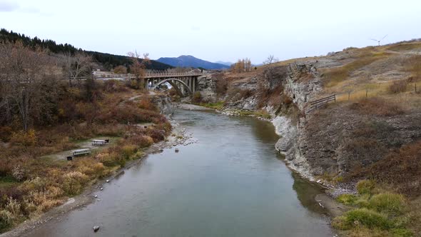 Aerial slow motion footage of an open spandrel deck arch bridge near lundbreck falls in Canadian pra