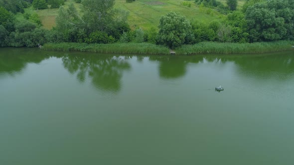 Aerial View Fisherman is Fishing Sitting on an Inflatable Boat in Lake