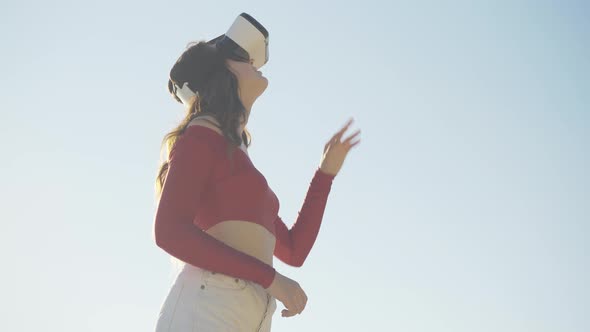 Middle Shot Portrait of Young Absorbed Woman Using Virtual Reality Simulator Outdoors. Slender