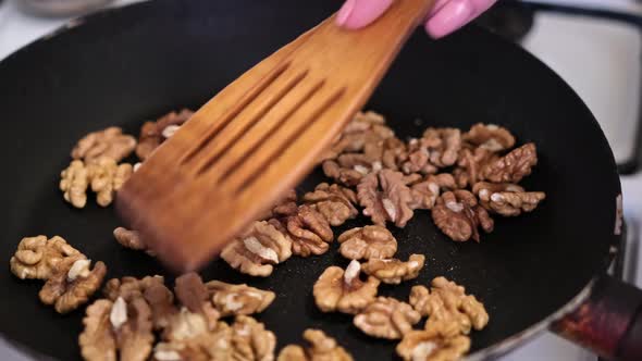 Closeup Video of of Walnuts Fried in Frying Pan Until Golden Brown and Mixed with Kitchen Spatula