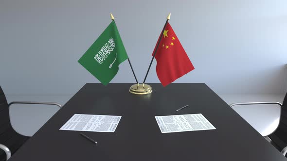 Flags of Saudi Arabia and China and Papers on the Table alt