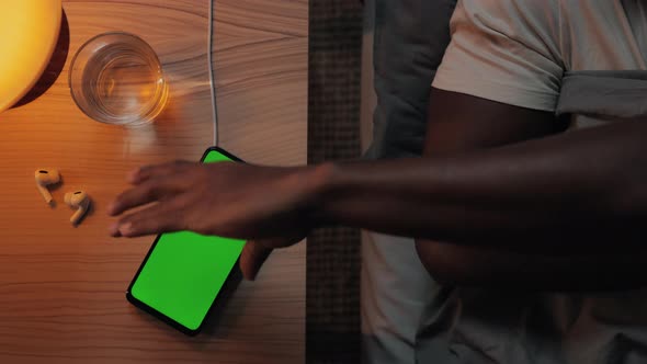 African American Man Putting Mobile on Wireless Charger Before Sleep