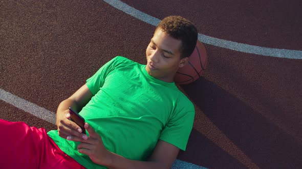 Basketball Player with Cellphone Resting on Court