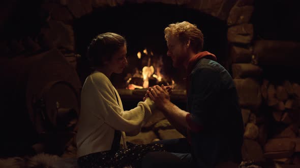 Young People Hold Hands By Fireplace