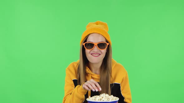 Portrait of Modern Girl in Yellow Hat in 3D Glasses Is Watching a Funny Movie and Eating Popcorn