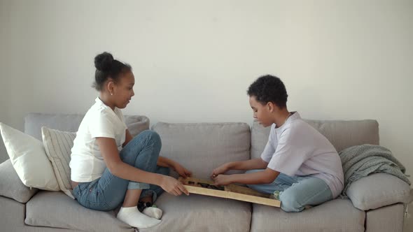 African American Brother and Sister Playing Chess on Couch at Living Room