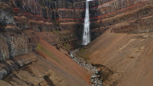 Aerial Static Footage of Hengifoss Waterfall Red Mountain Wall and River in Iceland