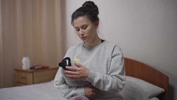 Brokenhearted Young Woman Caressing Hugging Toy Sitting in Bedroom at Home Indoors
