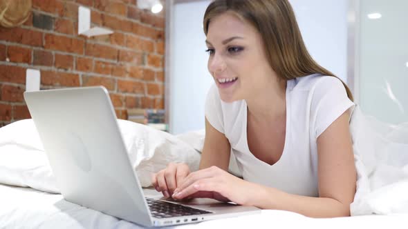 Online Video Chat on Laptop by Woman Lying in Bed at Night