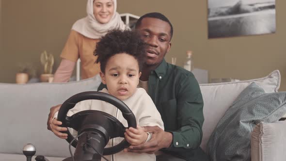 Little Boy Playing Race Game with Gaming Steering Wheel at Home