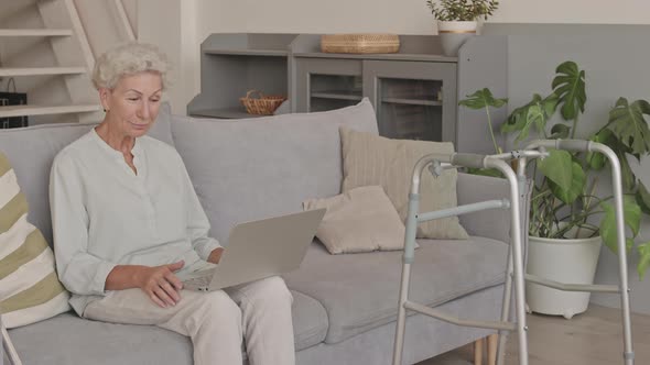 Old Lady Video Chatting on Laptop on Sofa