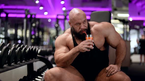 Portrait of a Male Bodybuilder in Sportswear Opening a Freshly Squeezed Juice in Training