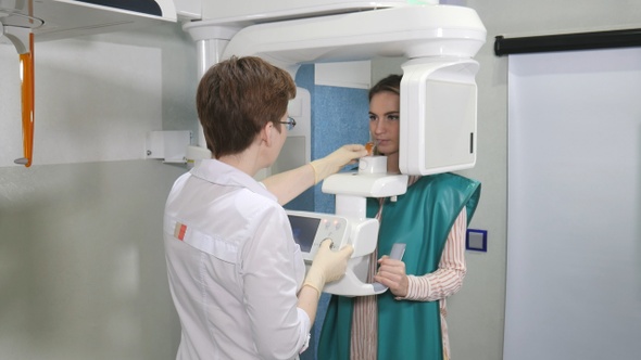 Female patient undergoes panoramic skull scan of teeth