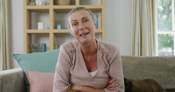 Portrait of happy senior caucasian woman sitting and making video call with cat in living room