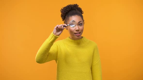 Curious African American Woman Looking Through Magnifying Glass, Having Fun