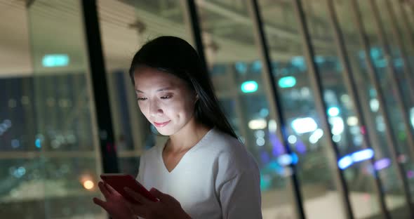 Woman look at mobile phone in city at night