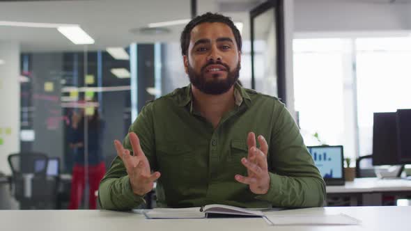 Happy mixed race businessman sitting at desk having video call