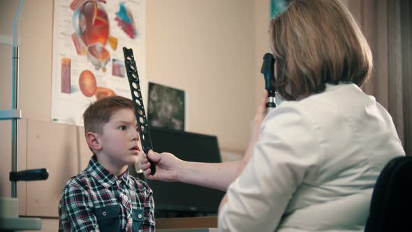 A Little Boy Having a Treatment in Eye Clinic - a Woman Doctor Checking an Eye Visibility of a