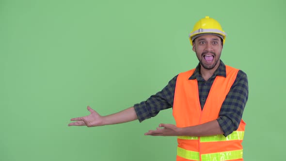 Happy Young Bearded Persian Man Construction Worker Showing Something and Looking Excited