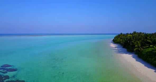 Natural above tourism shot of a white sandy paradise beach and aqua blue ocean background in 4K