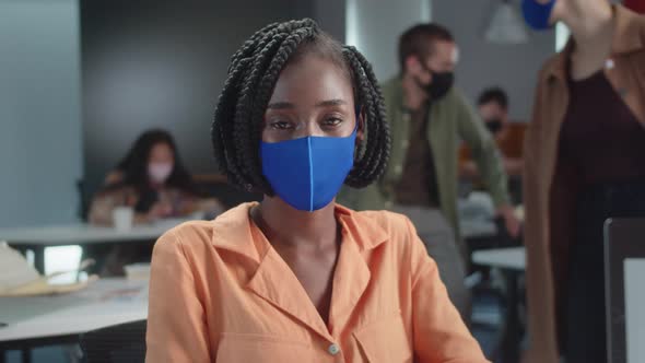 A Young African Professor is Sitting in a Blue Protective Mask with Her Students in the Classroom