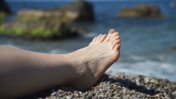 Female Legs on the Background of the Beach on the Sea of Pebbles. Rest and Relaxation, Slow Motion