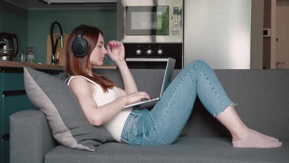 A Beautiful Woman with Works on Couch Behind a Laptop