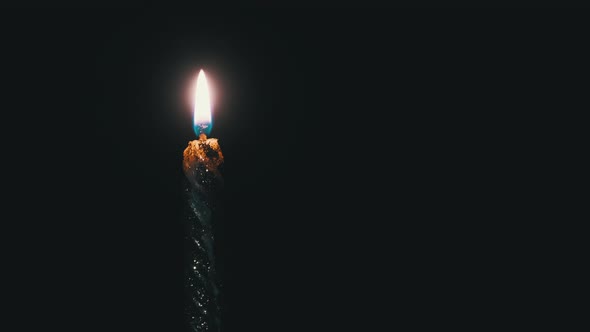 A Single Candle Is Lit on a Black Background. Candle Flame in the Dark.