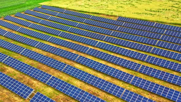 Flying above of solar panels on field in summer alt