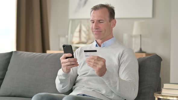 Excited Middle Aged Man Making Successful Payment on Smartphone 