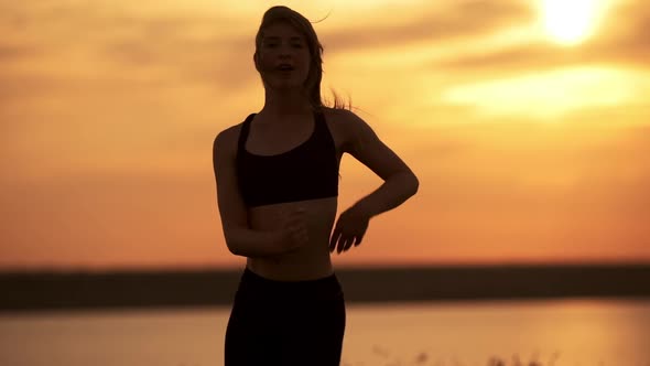 Silhouette of Young Beautiful Girl Dancing Zumba in Field at Sunrise