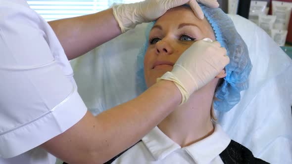 Beautician Hands in Rubber Gloves Clean Skin of Client in Beauty Salon