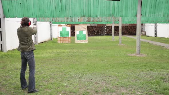 A Man in Protective Headphones Strips From a Gun on Green Targets in the Dash