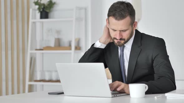 Businessman with Neck Pain Working on Laptop