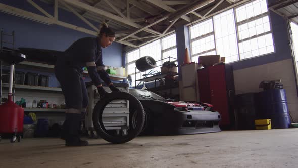 Female mechanic rolling a tire to change at a car service station