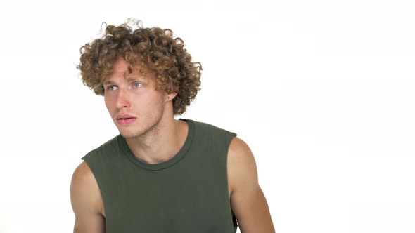 Portrait of Concentrated Guy with Curly Hair in Green Muscle Shirt Scanning Aroung Making Visual