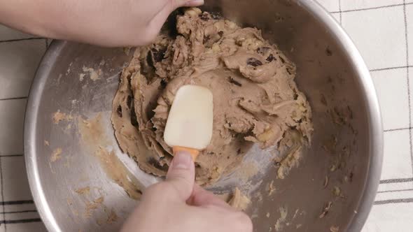 Person Mixing Cookie Dough Using Spatula On Stainless Bowl. - Topdown Shot