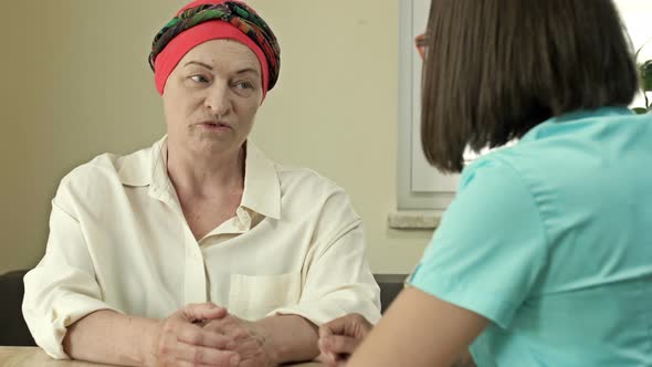 Cancer Female Patient Wearing a Headscarf After Chemotherapy Consults with an Oncologist