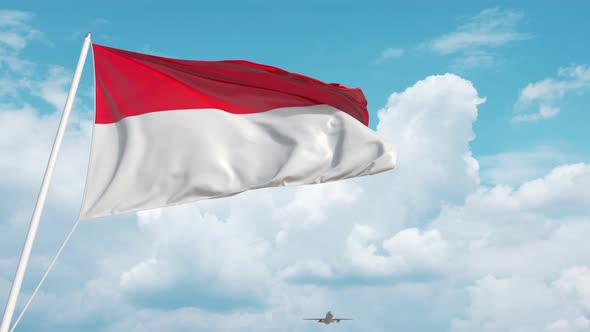 Commercial Airplane Landing Behind the Indonesian Flag