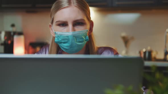 Medium Shot of Computer Monitor and Woman in Medical Mask Reading Something on It