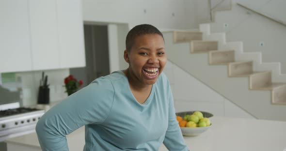 Portrait of smiling african american plus size woman looking at camera in kitchen