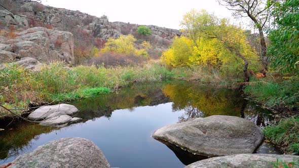 A Fast Clean Stream Runs Among Smooth Wet Stones Surrounded By Tall Dry Lumps