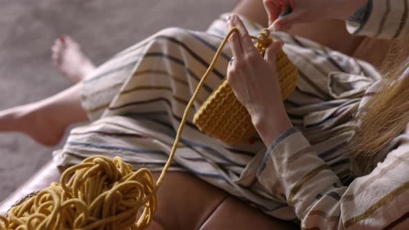 Woman Crocheting a Handbag using Knit Needles, Close Up, Copy Space, Over the Shoulder
