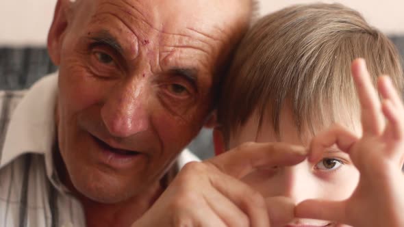 Portrait of happy Caucasian male over 70 and boy 6-7 years old showing ruami heart gesture